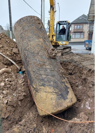 Grande cuve enterrée extraite d’une fouille par une pelle mécanique sur un terrain en zone urbaine, dans le cadre de travaux de dépollution et d’assainissement des sols supervisés par Aquaconseil.
